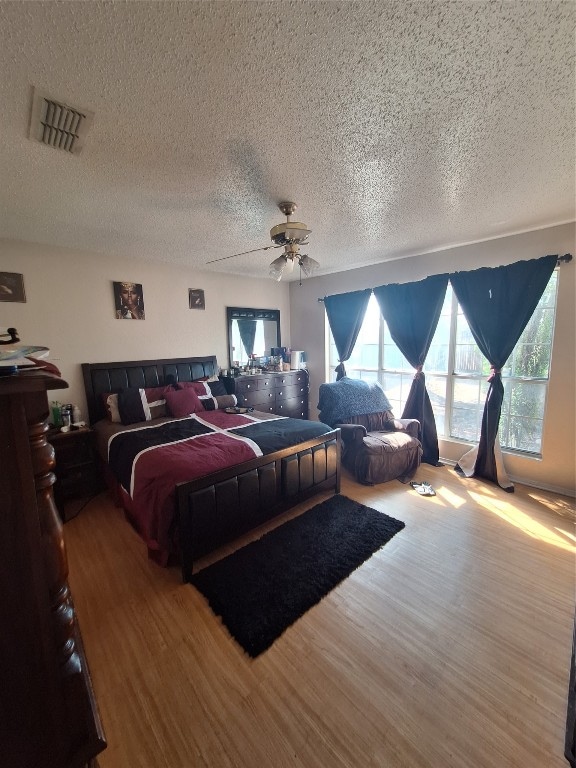 bedroom with a textured ceiling, ceiling fan, and wood-type flooring