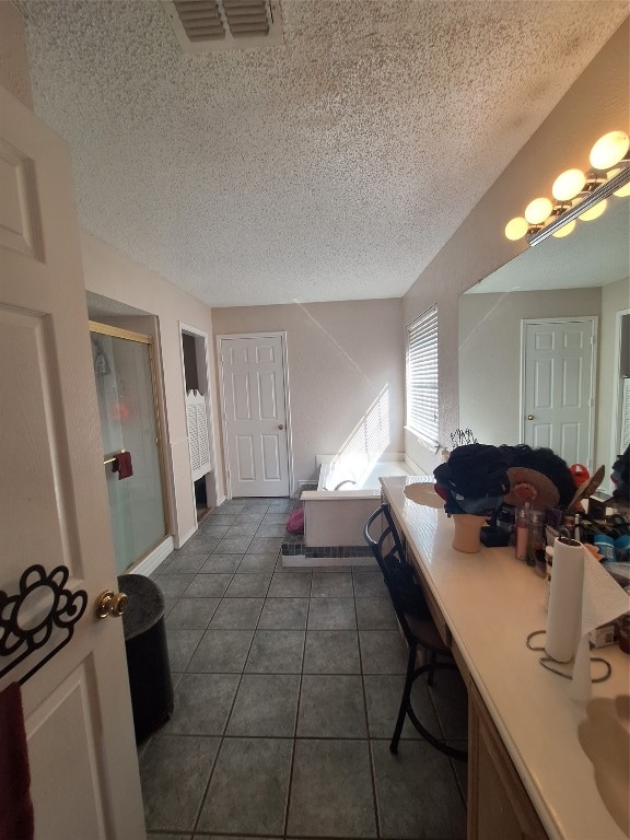 bathroom with a textured ceiling, tile flooring, and independent shower and bath