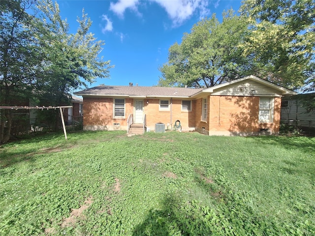 rear view of house featuring central AC and a lawn