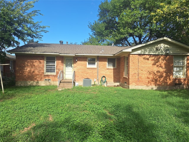 rear view of house featuring central air condition unit and a lawn