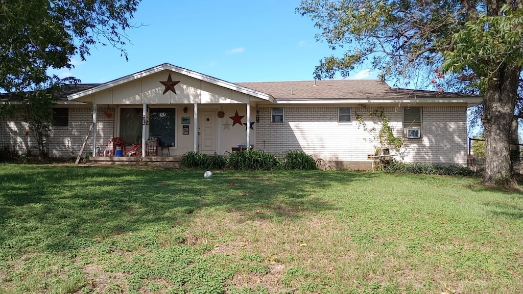 ranch-style home featuring a front lawn and covered porch