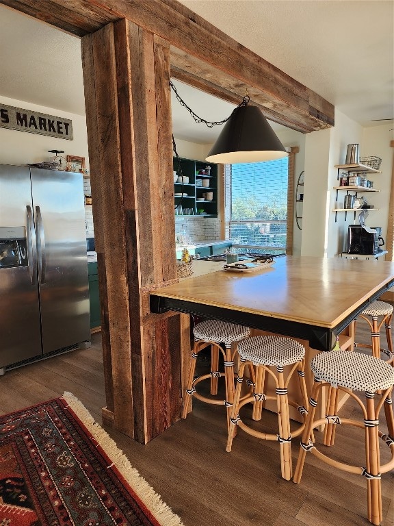 kitchen with hanging light fixtures, tasteful backsplash, a kitchen bar, dark hardwood / wood-style flooring, and stainless steel refrigerator with ice dispenser