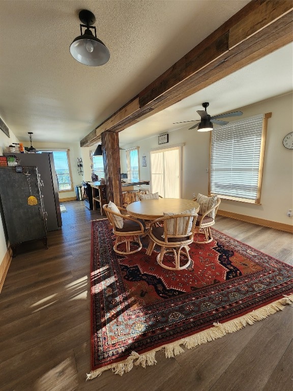 dining room featuring ceiling fan, a textured ceiling, dark hardwood / wood-style floors, and beam ceiling