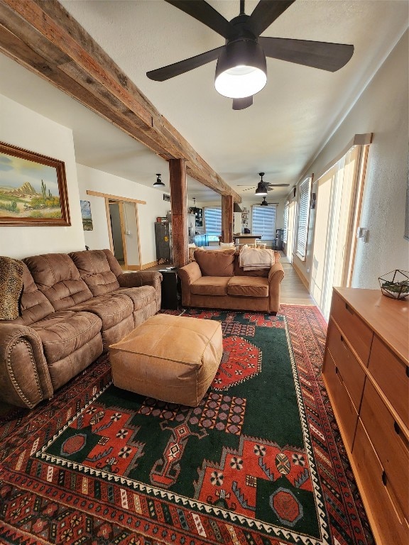 living room with ceiling fan, dark hardwood / wood-style floors, and beamed ceiling