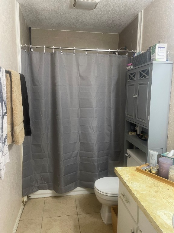 bathroom featuring toilet, tile flooring, a textured ceiling, and vanity