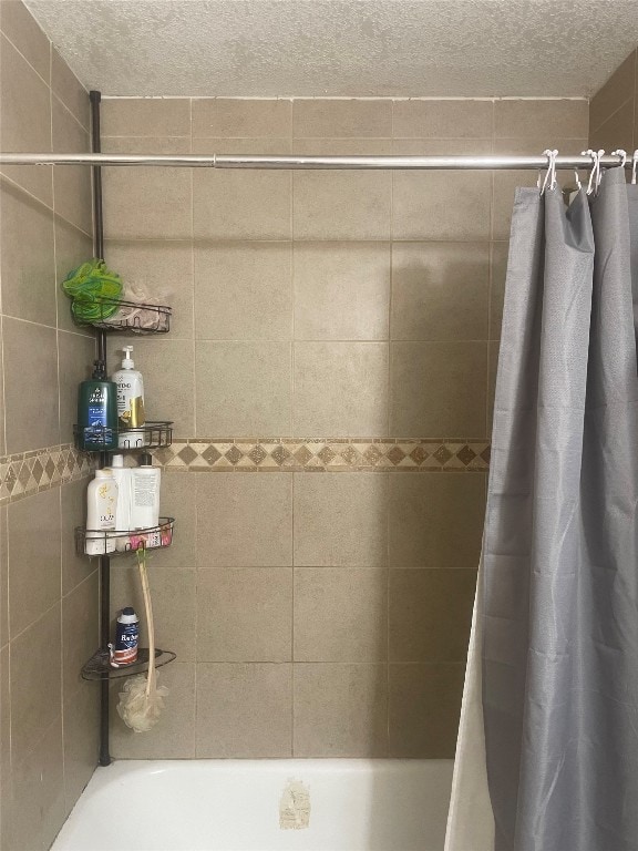 bathroom with shower / bathtub combination with curtain and a textured ceiling