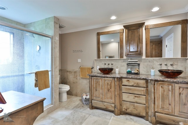 bathroom featuring vanity, toilet, a shower with door, and tile walls