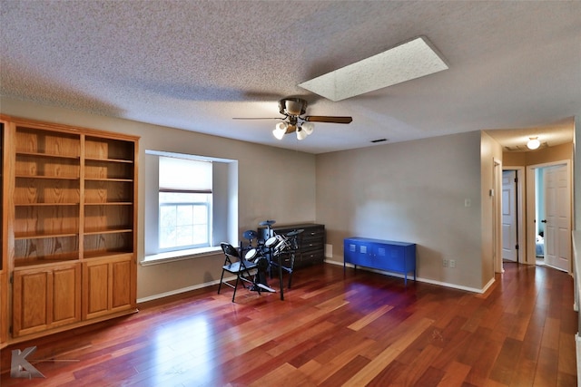 sitting room with a textured ceiling, dark hardwood / wood-style flooring, a skylight, and ceiling fan