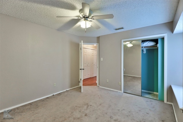 unfurnished bedroom with ceiling fan, light colored carpet, and a textured ceiling