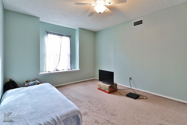 carpeted bedroom with ceiling fan and a textured ceiling