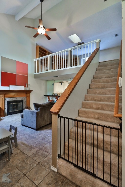 stairs with ceiling fan, beam ceiling, and high vaulted ceiling