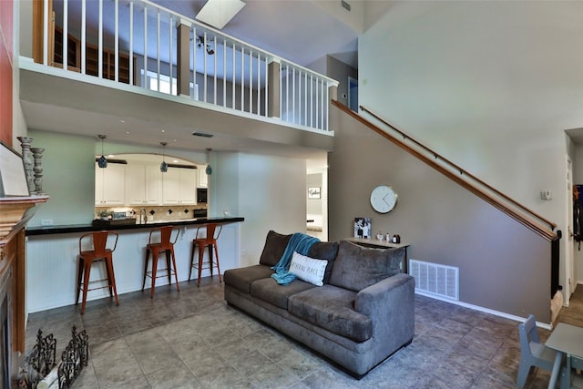 living room featuring ceiling fan and a towering ceiling