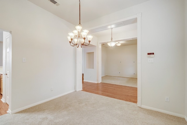 empty room featuring light hardwood / wood-style floors and a chandelier