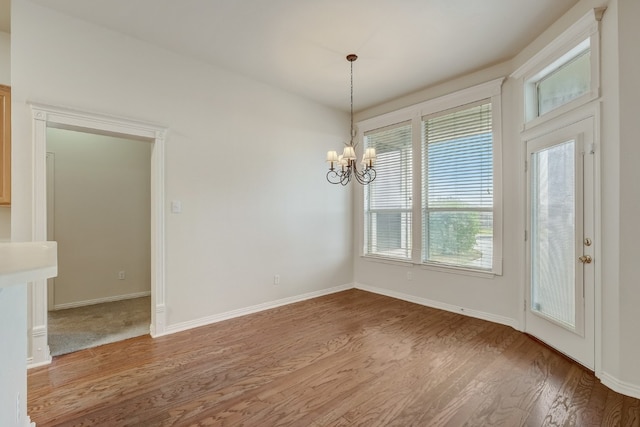 spare room featuring a chandelier and dark wood-type flooring