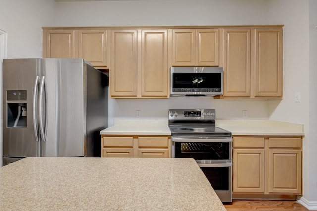 kitchen with light brown cabinetry, stainless steel appliances, and light hardwood / wood-style floors