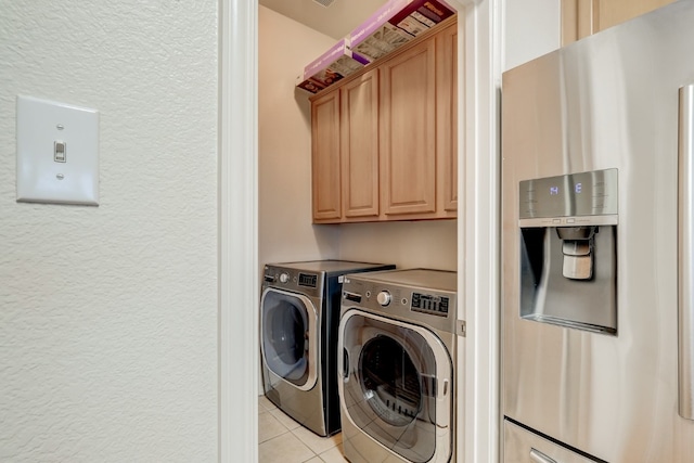 laundry room with washer and clothes dryer, cabinets, and light tile floors