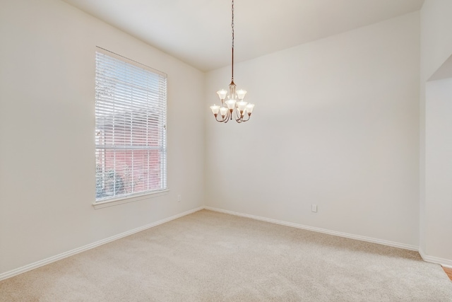 spare room with a notable chandelier, light carpet, and plenty of natural light