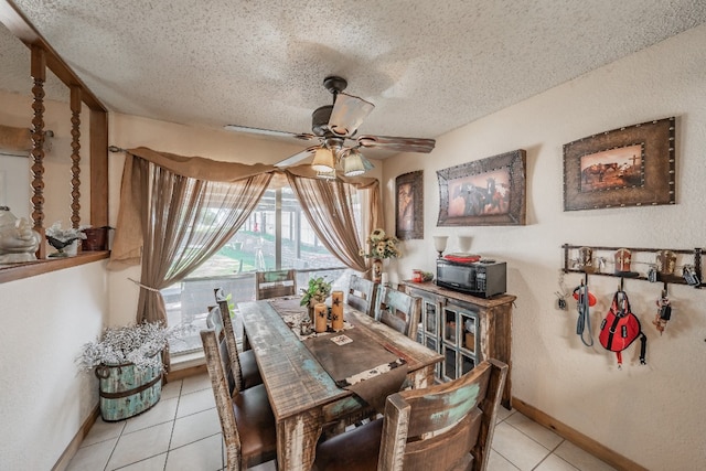 tiled dining space featuring a textured ceiling and ceiling fan