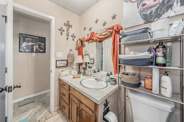 bathroom featuring toilet, tile floors, a textured ceiling, and vanity