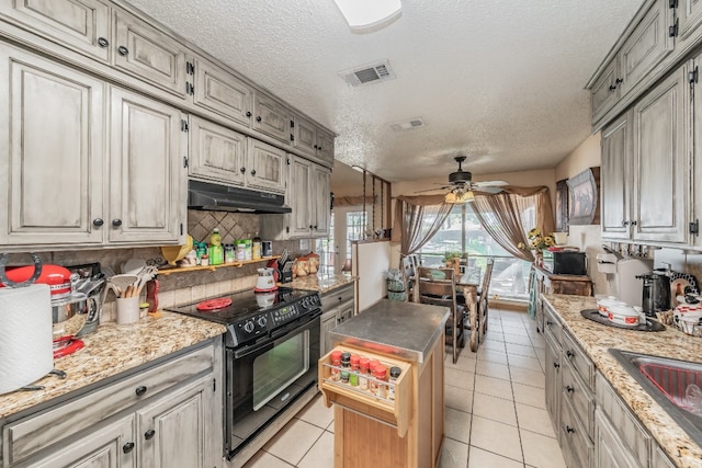 kitchen featuring light tile floors, a center island, ceiling fan, electric range, and backsplash