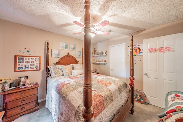 bedroom featuring a textured ceiling, light colored carpet, and ceiling fan