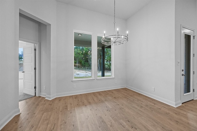 unfurnished dining area with light hardwood / wood-style flooring and a notable chandelier