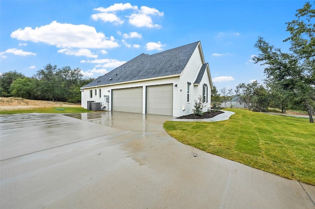 view of side of property with central AC, a yard, and a garage