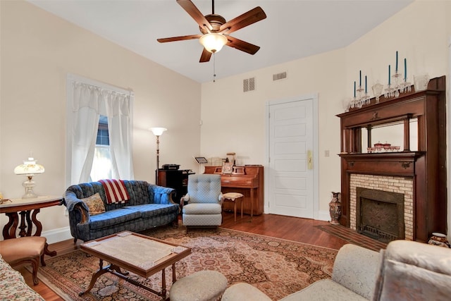 living room with ceiling fan, dark hardwood / wood-style flooring, and a brick fireplace