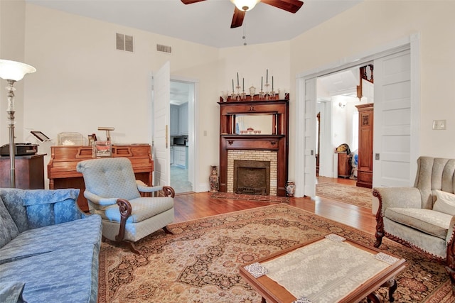 living room with ceiling fan, a fireplace, and hardwood / wood-style flooring