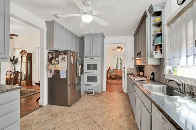 kitchen with light tile floors, ceiling fan, stainless steel refrigerator, and tasteful backsplash