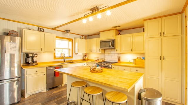 kitchen featuring a kitchen breakfast bar, stainless steel appliances, a center island, and wood counters