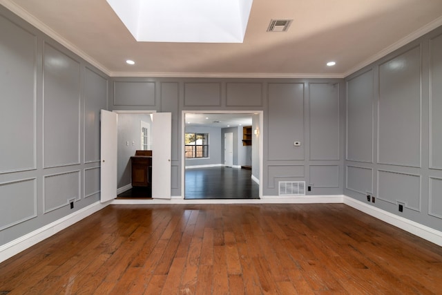 unfurnished living room with ornamental molding, a skylight, and dark wood-type flooring