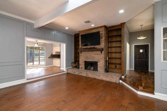 unfurnished living room with brick wall, dark wood-type flooring, a fireplace, and beamed ceiling