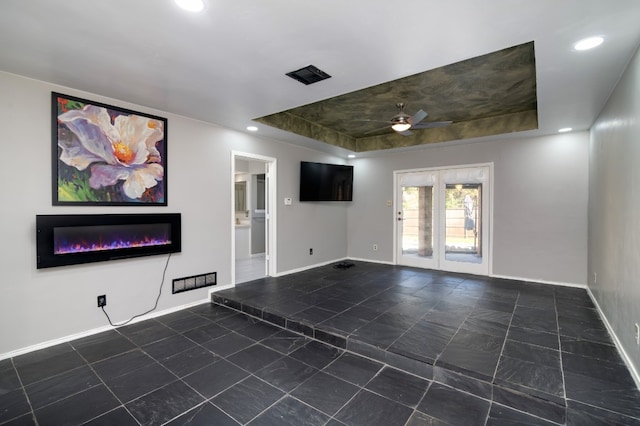 tiled empty room with a raised ceiling and ceiling fan