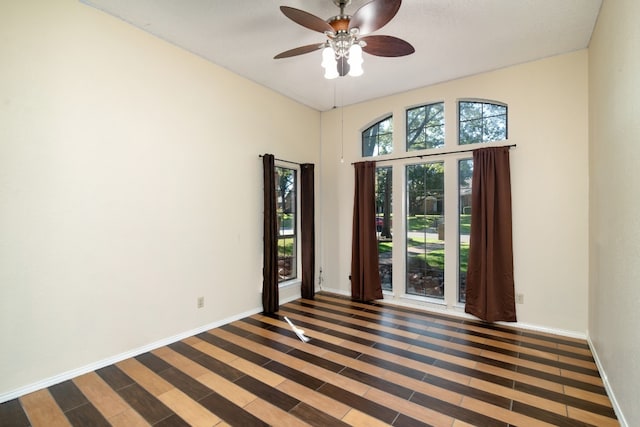 empty room featuring dark hardwood / wood-style flooring, ceiling fan, and a high ceiling