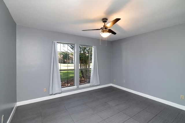 spare room with dark tile flooring and ceiling fan