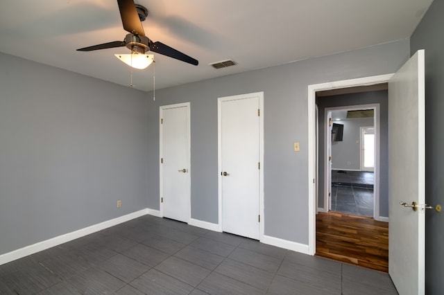 unfurnished bedroom with ceiling fan and dark wood-type flooring