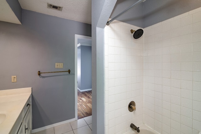 bathroom with vanity, tiled shower / bath combo, a textured ceiling, and tile floors