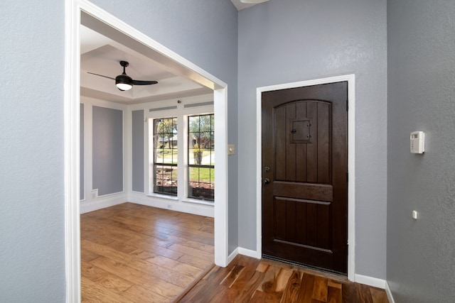 entrance foyer featuring a raised ceiling, dark wood-type flooring, and ceiling fan