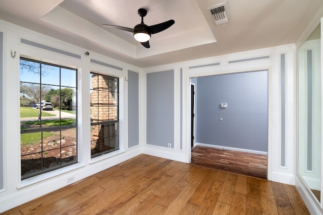 unfurnished room featuring dark hardwood / wood-style flooring, ceiling fan, and a raised ceiling