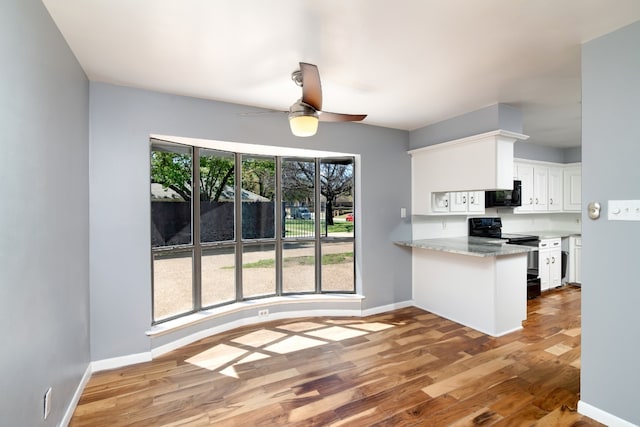 kitchen with kitchen peninsula, ceiling fan, wood-type flooring, light stone countertops, and white cabinetry