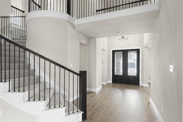 foyer entrance featuring french doors, a towering ceiling, and hardwood / wood-style flooring