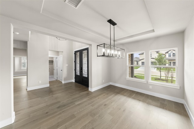 unfurnished dining area featuring hardwood / wood-style flooring and a raised ceiling