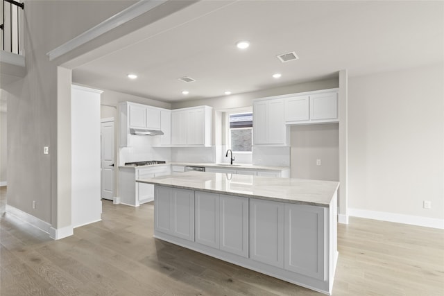 kitchen featuring white cabinetry, a kitchen island, sink, and stainless steel gas cooktop