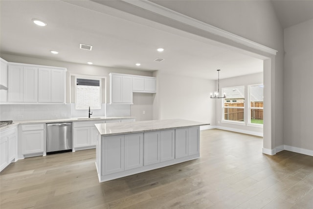 kitchen with sink, dishwasher, hanging light fixtures, white cabinets, and a kitchen island