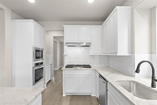 kitchen with sink, light wood-type flooring, white cabinets, and appliances with stainless steel finishes