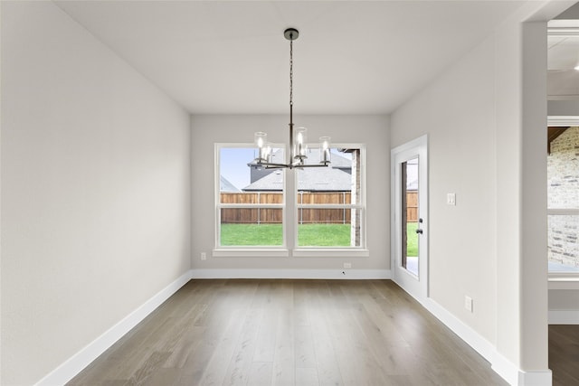 unfurnished dining area with hardwood / wood-style floors and a notable chandelier