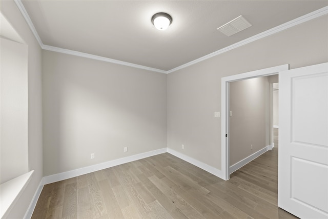 spare room featuring ornamental molding and light wood-type flooring