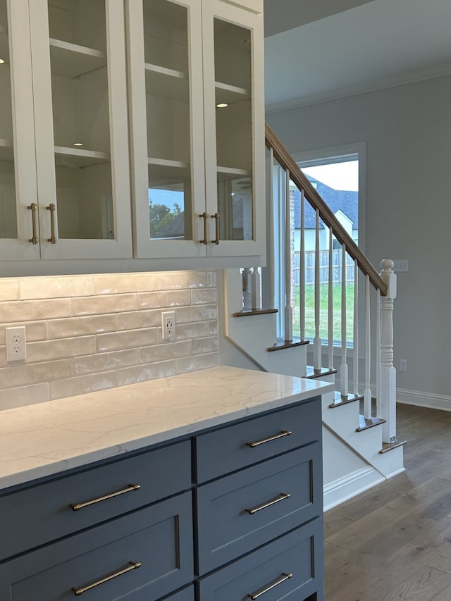 kitchen with decorative backsplash, crown molding, and light stone countertops