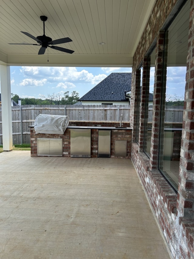 view of patio / terrace featuring a sink, exterior kitchen, a ceiling fan, and fence